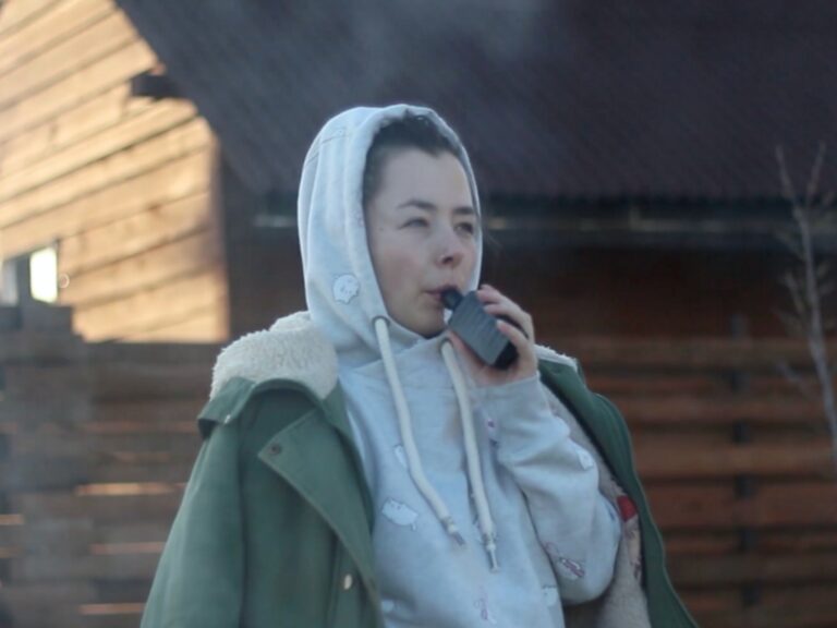 Lady smoking a vape wearing a hoody